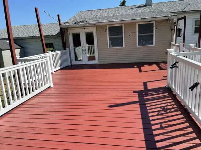 Red-painted wood deck with white railings and French doors to a two-story home